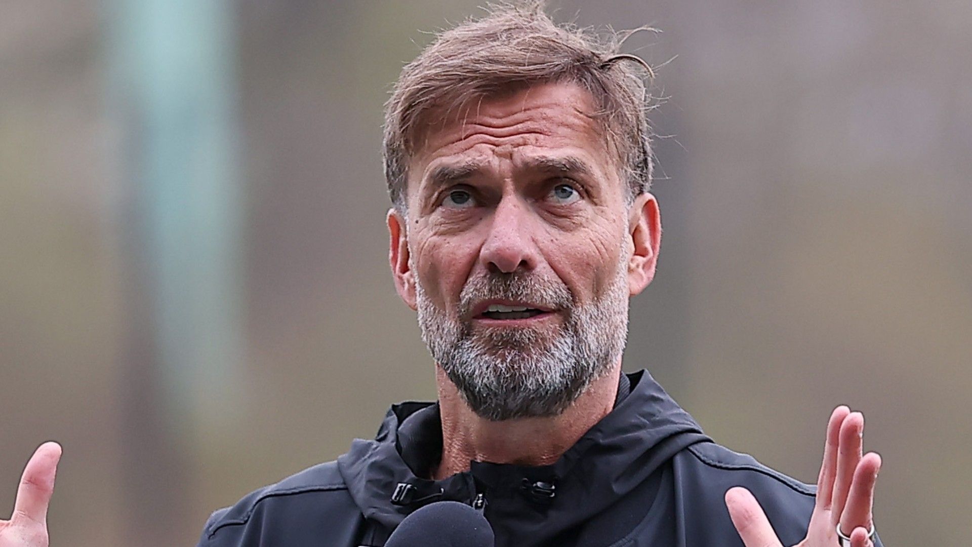 Jürgen Klopp tersenyum dengan latar bendera Jerman